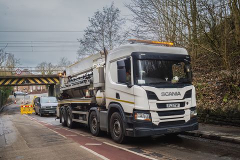 A jetting tanker on a road beside a railway bridge during network works