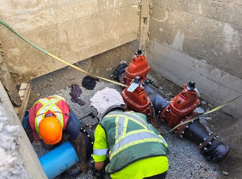 Operatives working on water main sluice valves in a shored excavation