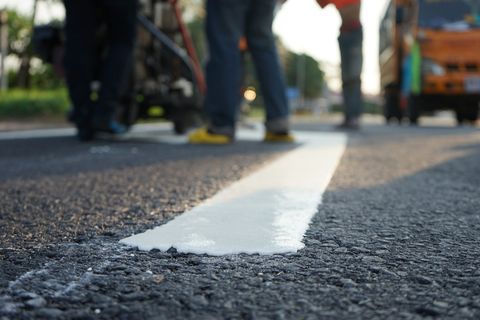 A fresh white line being painted onto a newly surfaced road