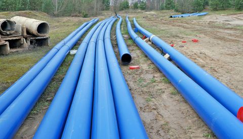 Long strings of blue water main pipe laid out on a site ready for installation