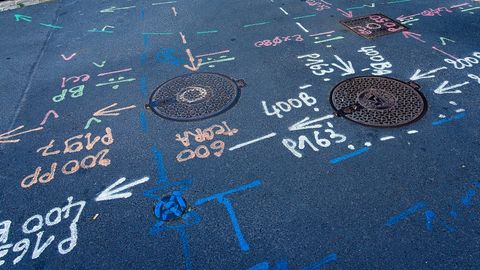 Utility survey markings sprayed on a road around manhole covers