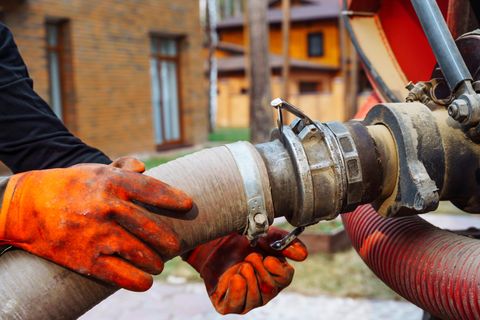 An operative couples a suction hose to a tanker during sewer maintenance