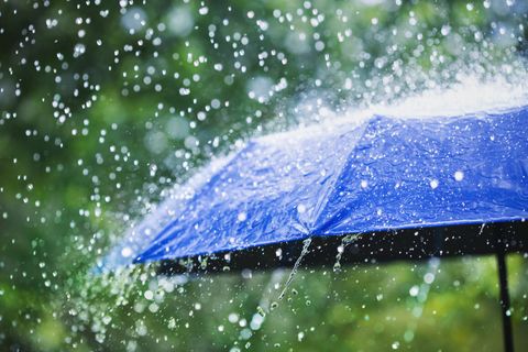 Heavy rain falling on a blue umbrella