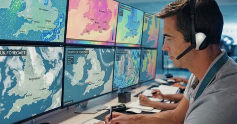 An operator monitors banks of screens showing UK weather forecasts in a control room