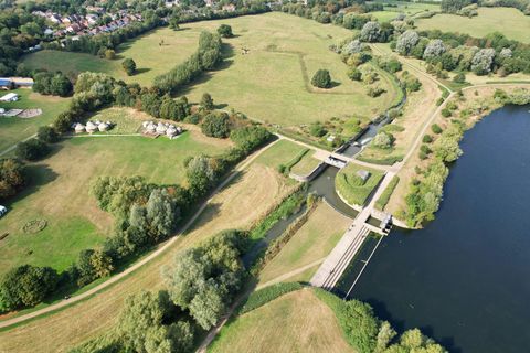 An aerial view of a river weir and sluice in open countryside