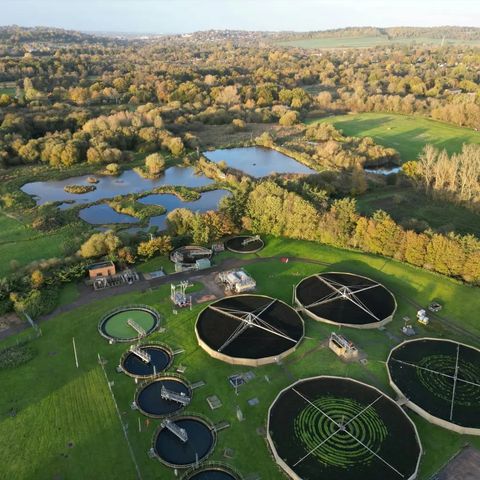 An aerial view of a sewage treatment works with circular clarifiers in open countryside